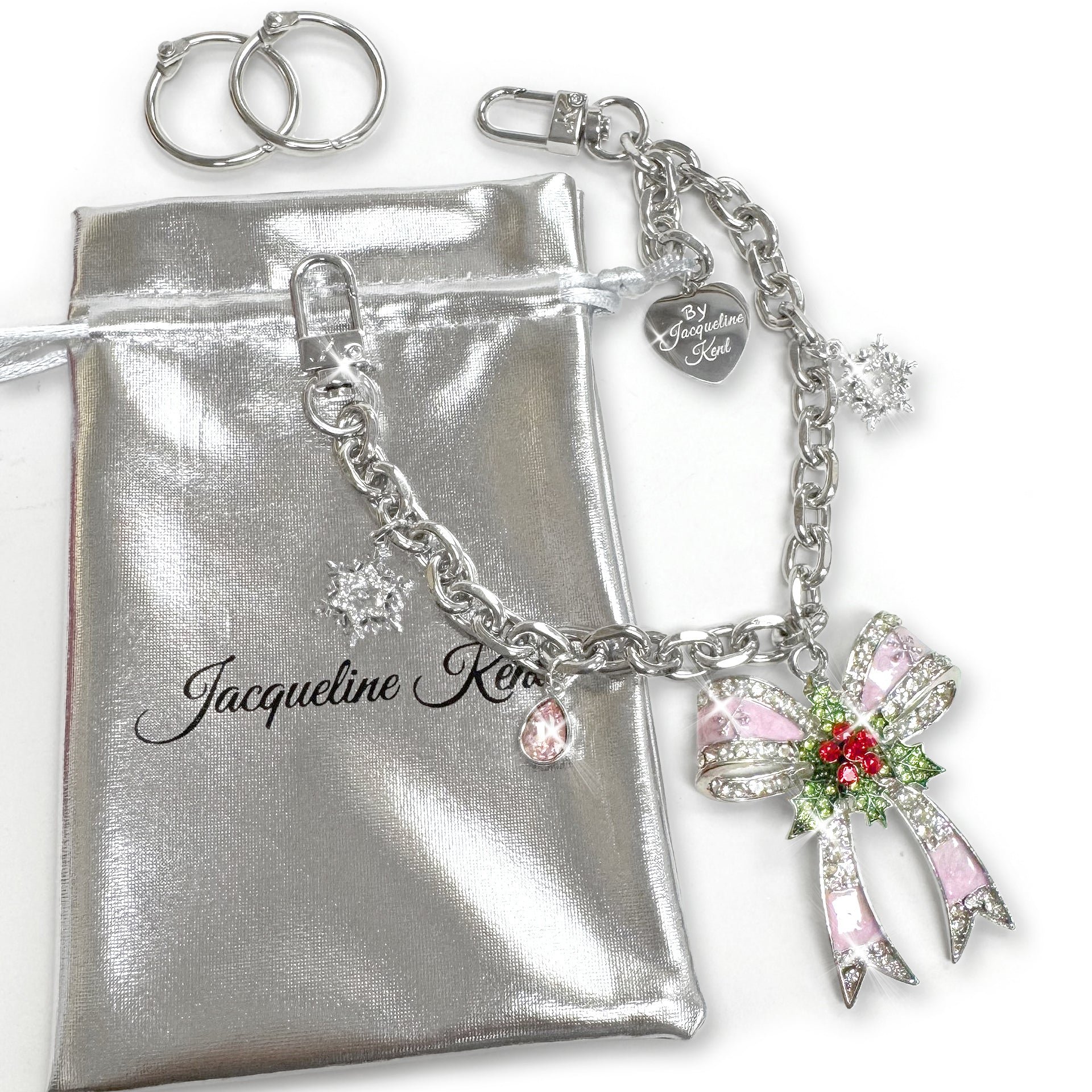 Silver Christmas bow purse charm chain with red enamel, clear, green and pink rhinestone details with a snowflakes and pink jewel charm with silver heart shaped branded Jacqueline Kent tag