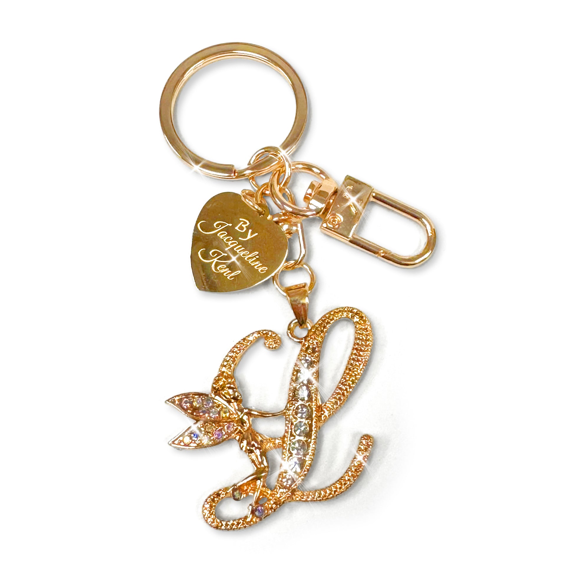 Gold and crystal embellished keychain with decorative letter 'L' and heart-shaped Jacqueline Kent branded tag on a white background