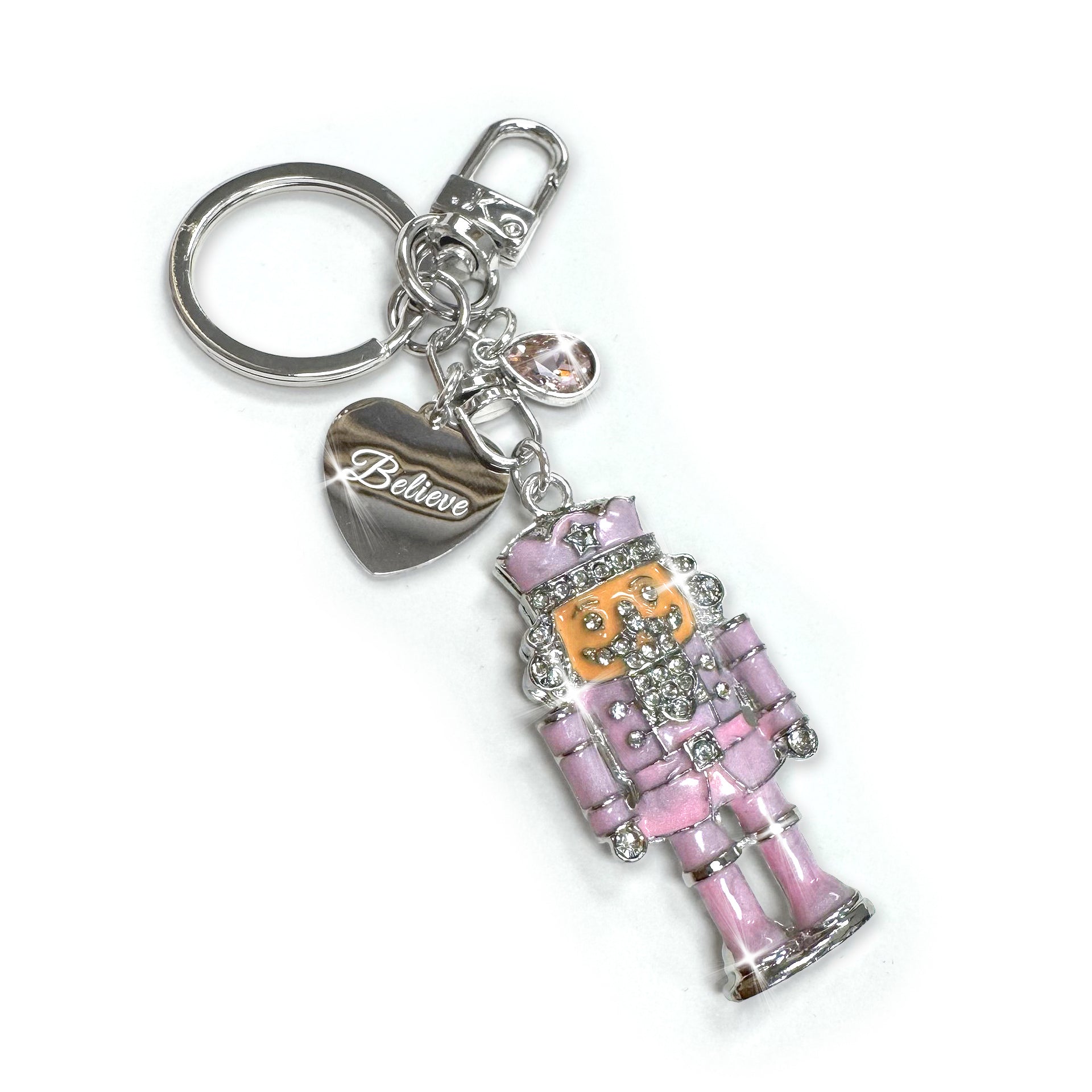 Keychain with pink enamelled nutcracker charm with clear rhinestones and 'Believe' heart on a white background