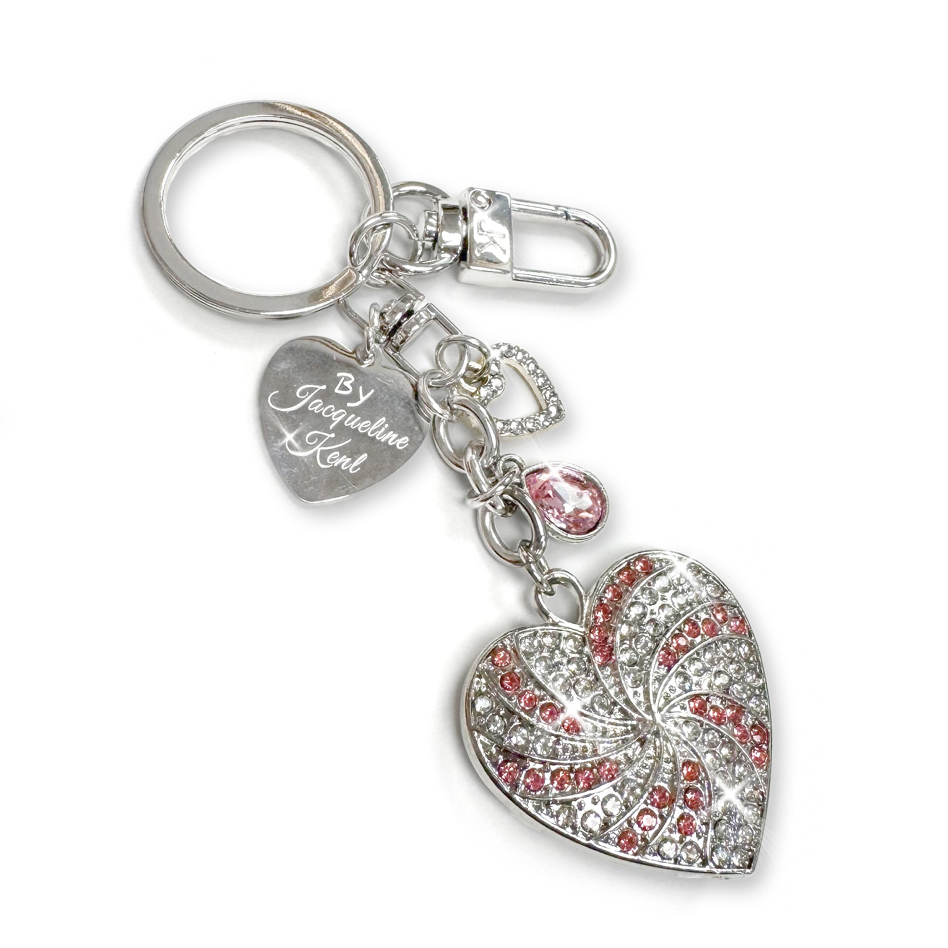 Clear and pink rhinestone encrusted silver heart-shaped purse charm/keychain in a spiral pattern with a Jacqueline Kent branded heart shaped tag and small crystal and heart shaped charms on a white background
