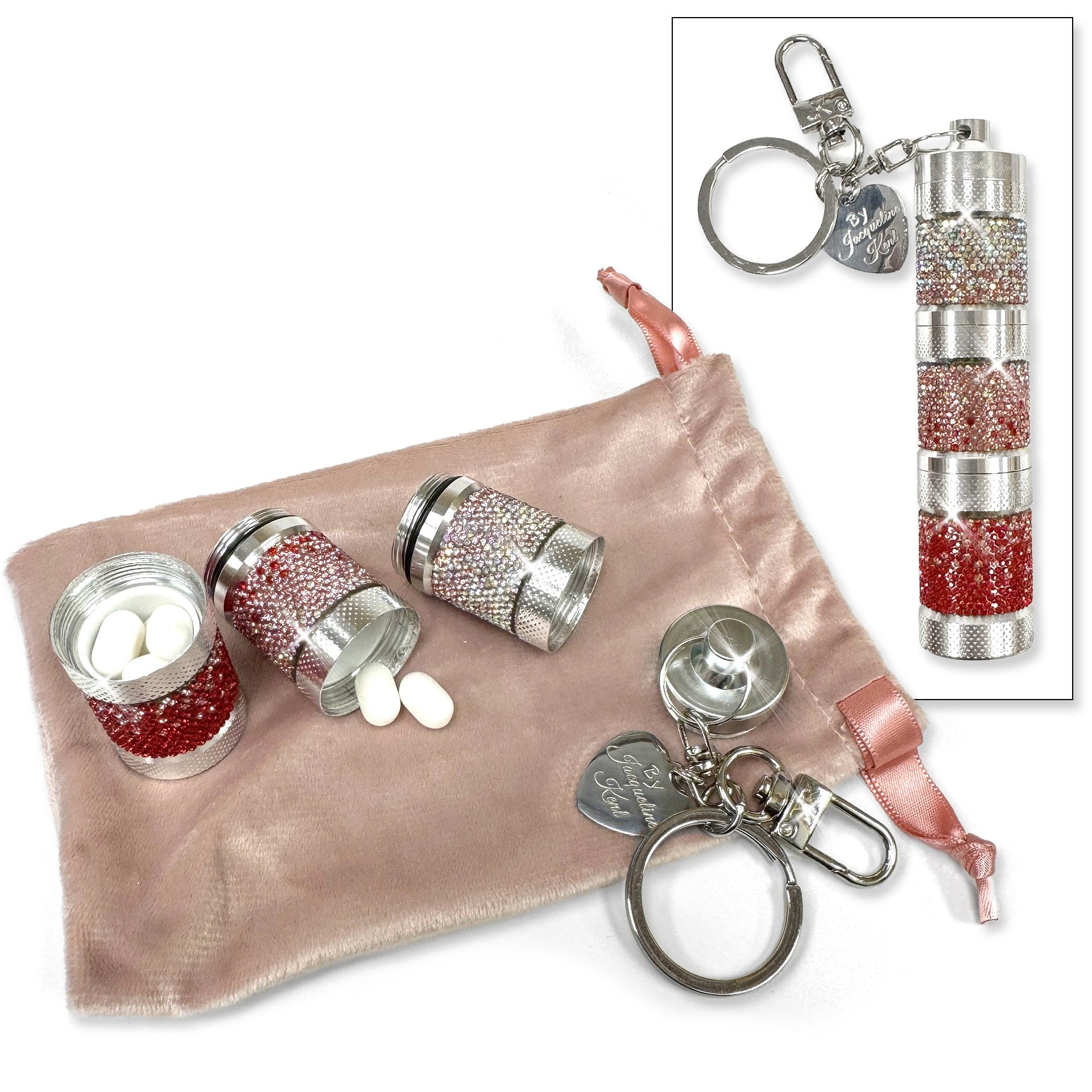 Silver and red rhinestone pill containers with keychains on a pink fabric background