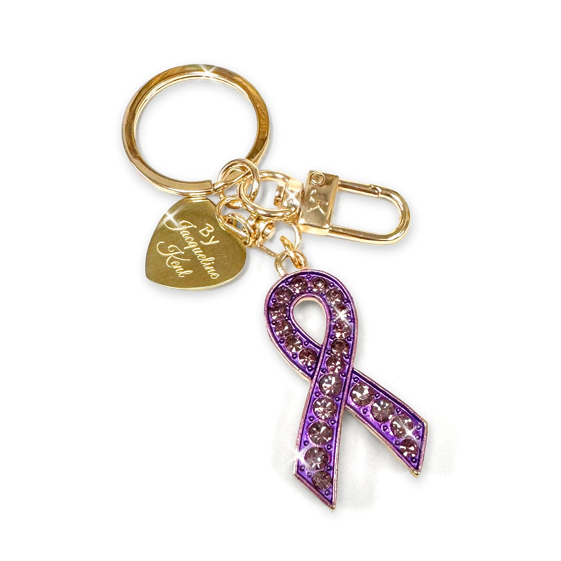 Gold purse charm/keychain with purple rhinestone ribbon charm and gold heart Jacqueline Kent branded tag on a white background