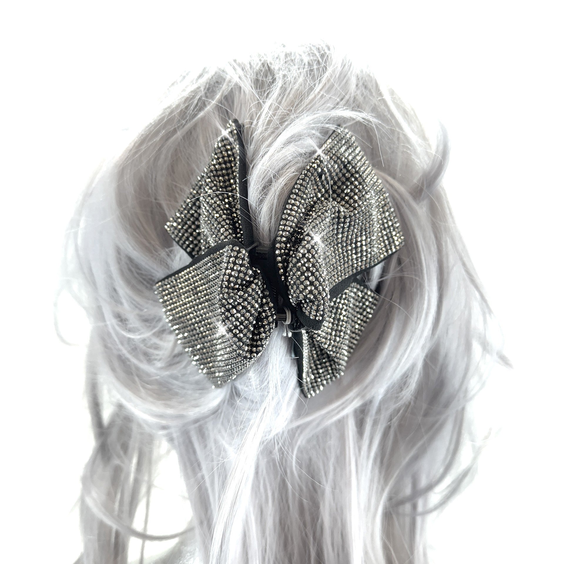 Hematite rhinestone bow hair clip on a white wig with long, wavy hair.