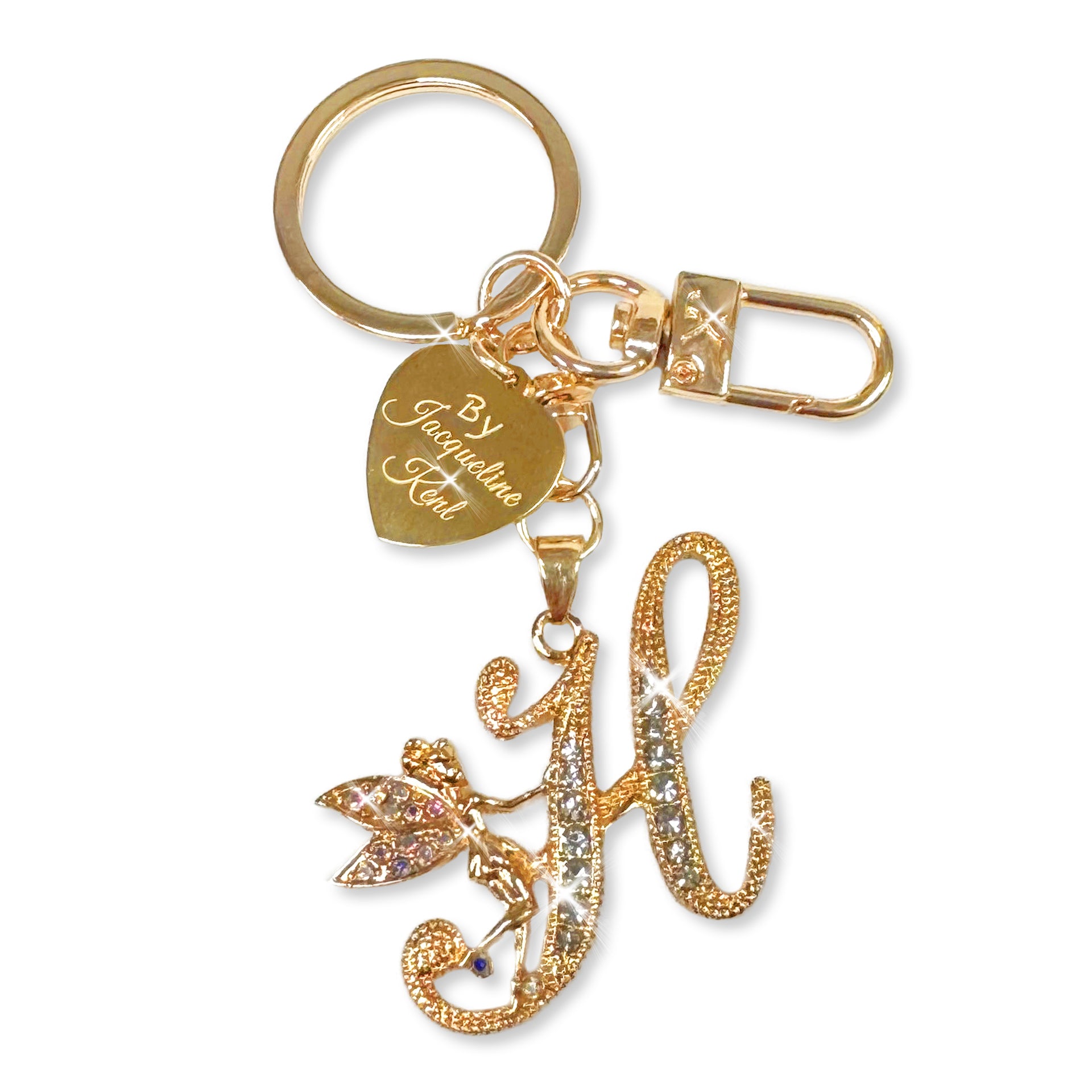 Gold and crystal embellished keychain with decorative letter 'H' and heart-shaped Jacqueline Kent branded tag on a white background
