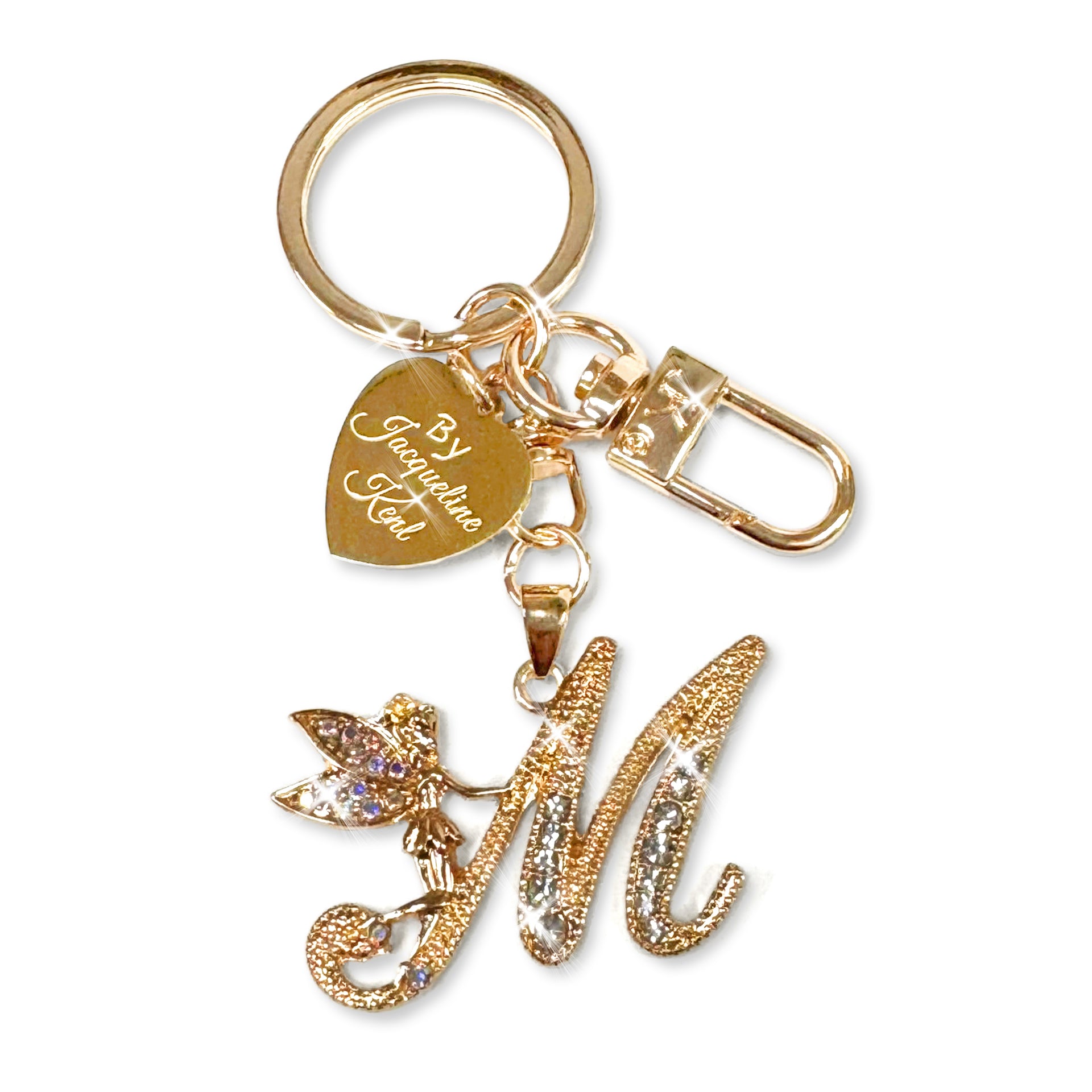 Gold and crystal embellished keychain with decorative letter 'M' and heart-shaped Jacqueline Kent branded tag on a white background