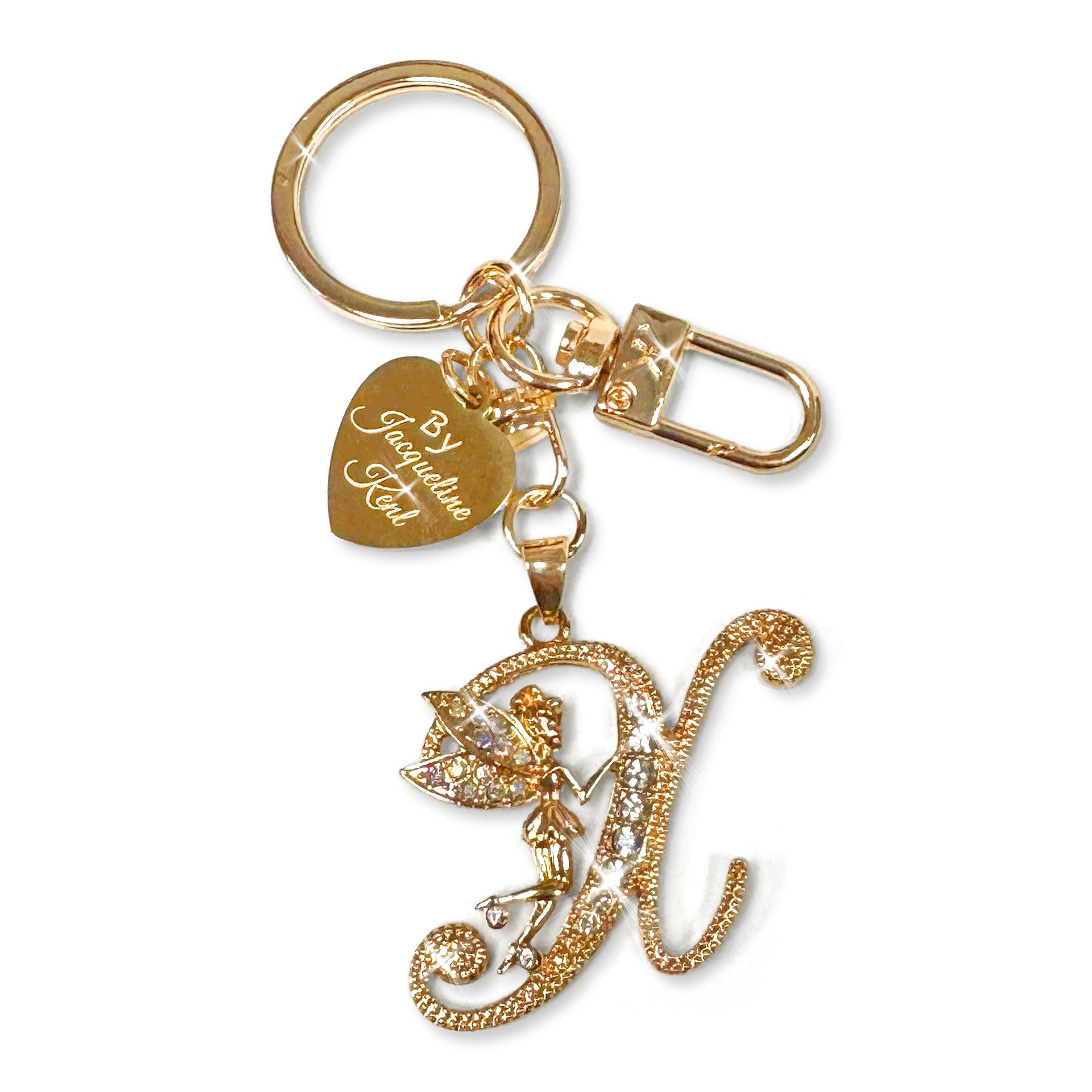 Gold and crystal embellished keychain with decorative letter 'X' and heart-shaped Jacqueline Kent branded tag on a white background