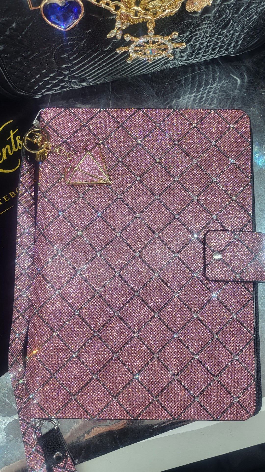 Decorative notebook with pink and hematite rhinestone diamond cross  pattern on a dark background