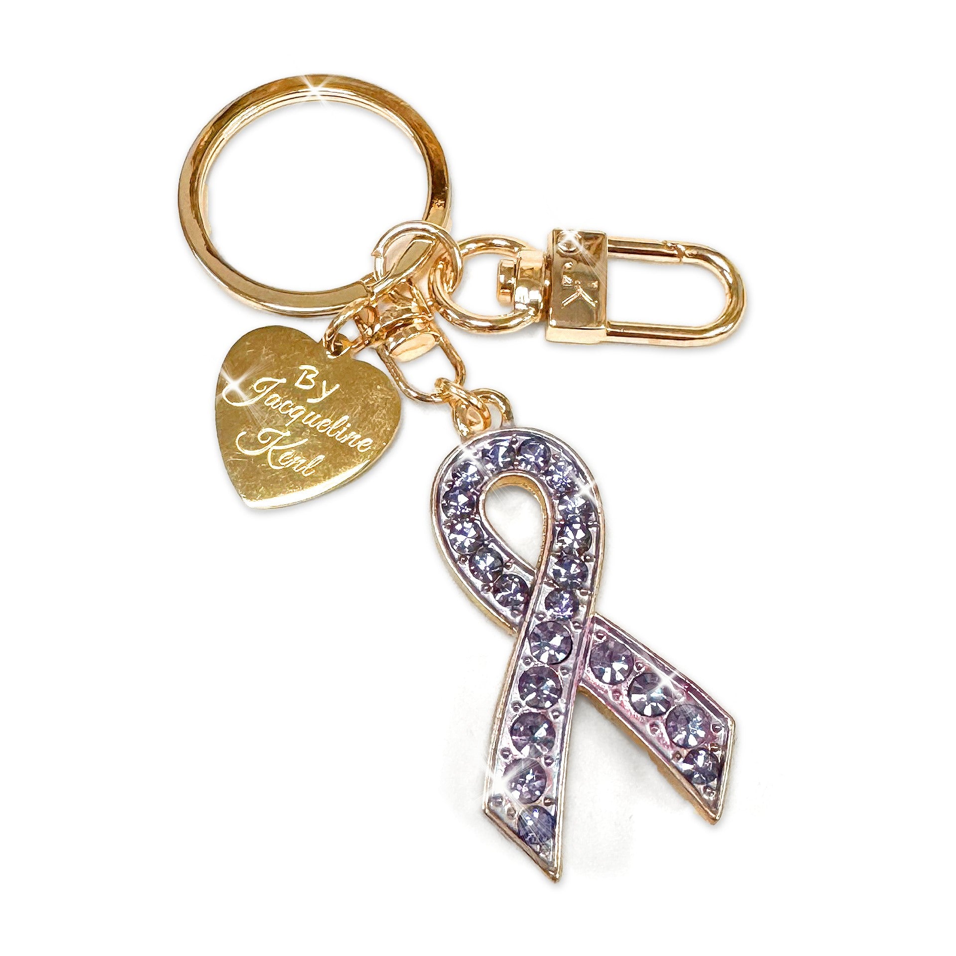 Gold purse charm/keychain with purple rhinestone ribbon charm and heart-shaped Jacqueline Kent branded tag on a white background